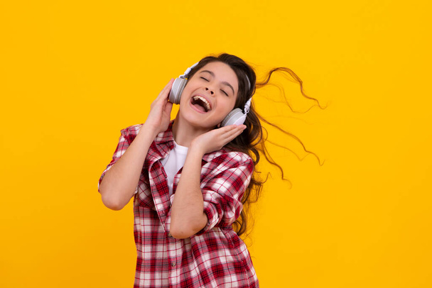 Funny kid girl 12, 13, 14 years old listen music with headphones. Teenage girl with headphones listening songs on headset earphone. Happy teenager, positive and smiling emotions of teen girl - Photo, Image