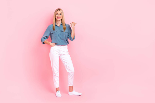 Full length photo of pretty cheerful person indicate thumb finger empty space isolated on pink color background. - Φωτογραφία, εικόνα