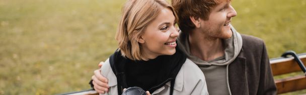 happy young man hugging blonde woman in autumnal coat, banner - Photo, image