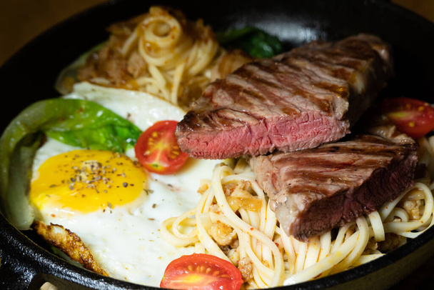 sliced steak with fried noodles on a plate at home - Foto, Bild