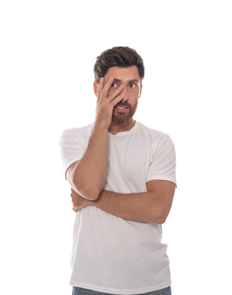 Embarrassed man covering face with hand on white background - Foto, afbeelding