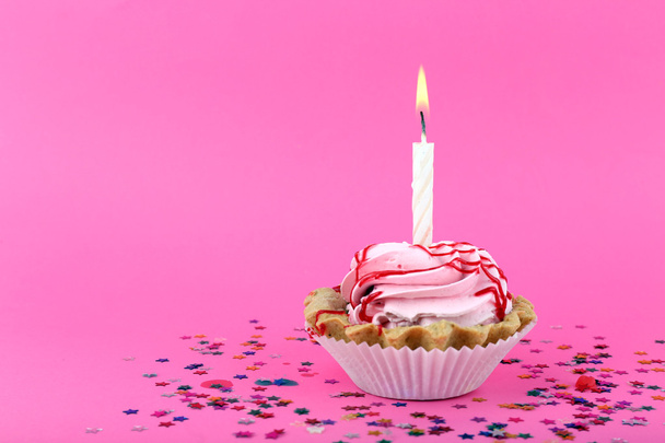 Birthday cup cake with candle and colorful stars on pink background - Foto, afbeelding