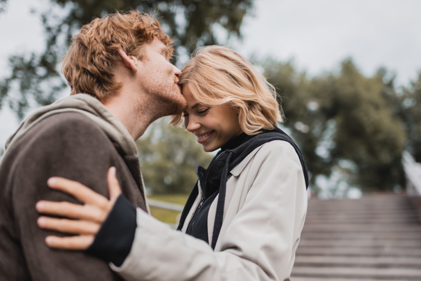 rossa uomo baciare fronte di felice fidanzata nel parco  - Foto, immagini