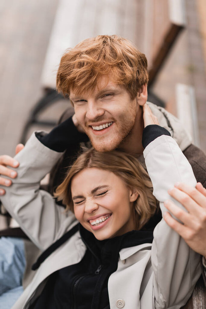 high angle view of cheerful young woman hugging smiling redhead man  - Fotoğraf, Görsel