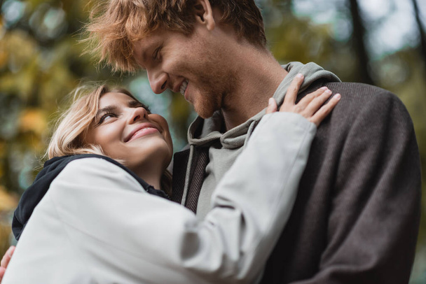 Blick auf ein glückliches Paar in Mänteln, das sich beim Date umarmt - Foto, Bild