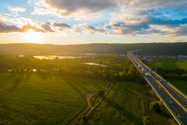 Cars and trucks traffic on highway bridge. Sunset flare on sunny summer evening. Lahovicky Bridge in Prague, Czech Republic. Aerial view from drone. - Foto, Imagem