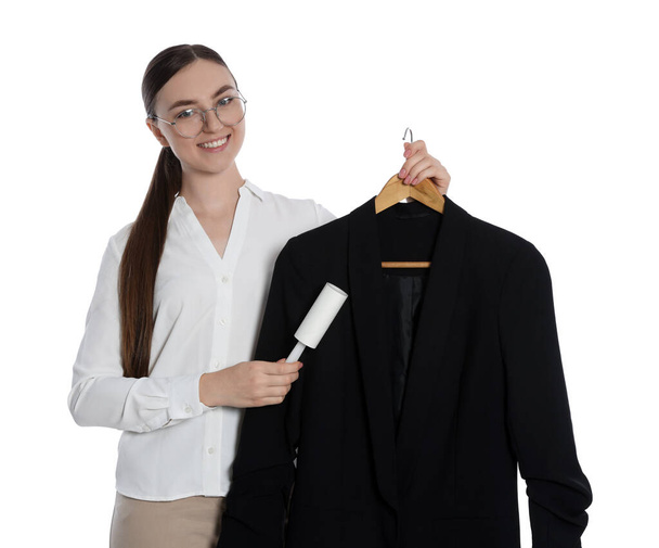 Young woman cleaning suit with lint roller on white background - Fotoğraf, Görsel