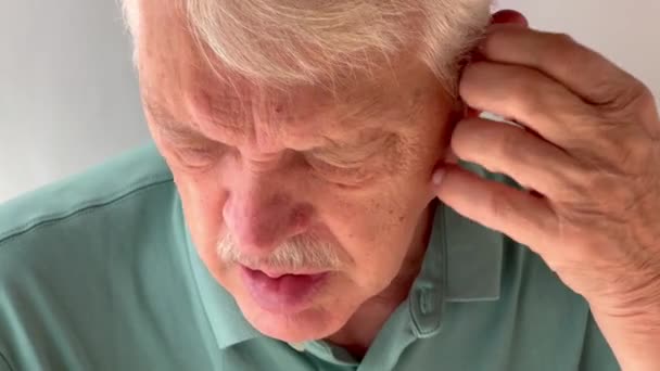 Senior se asegura de que sus audífonos se inserten correctamente - Metraje, vídeo