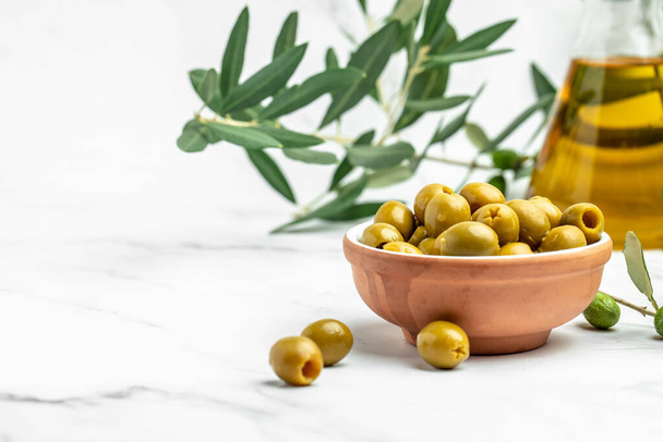 Větvička s olivami a láhev olivového oleje na bílém pozadí. pohled shora. místo pro text, - Fotografie, Obrázek