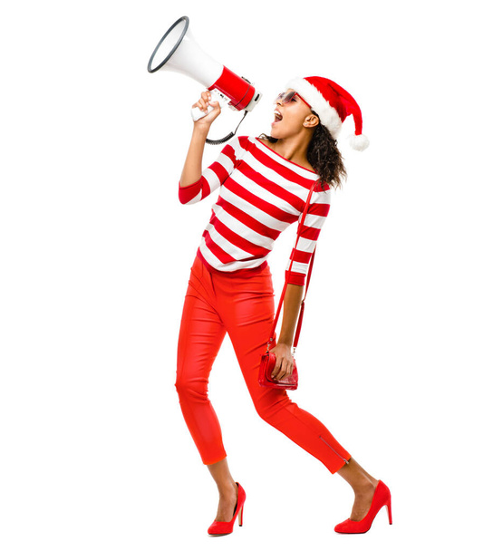 Des cris sur les dernières remises. une jeune femme portant un chapeau de Noël tenant un mégaphone posant sur un fond de studio - Photo, image