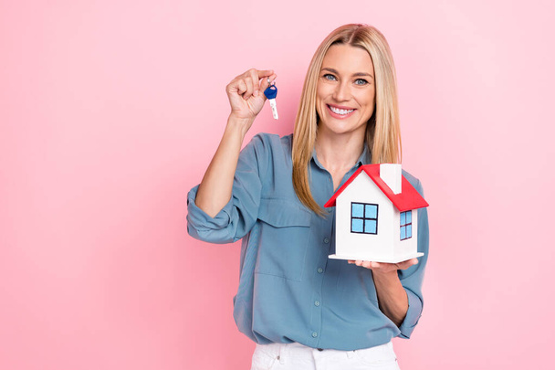 Photo of young positive realtor cute adorable lady wear smart casual clothes office hold new key house appartment isolated on pink color background. - 写真・画像
