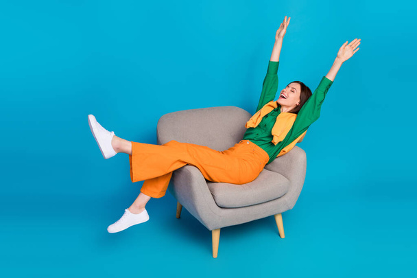 Full body portrait of cheerful lady sit chair closed eyes raise arms legs isolated on blue color background. - Foto, imagen