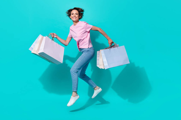 Full length photo of adorable girl pink t-shirt jeans white sneakers hold bags new outfit buy on sale isolated on teal color background. - Fotoğraf, Görsel