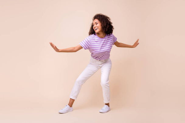 Full length photo of funny pretty lady wear violet t-shirt riding surf board isolated beige color background. - Фото, зображення