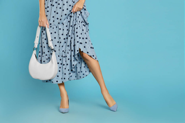 Woman with stylish bag on light blue background, closeup. Space for text - Zdjęcie, obraz