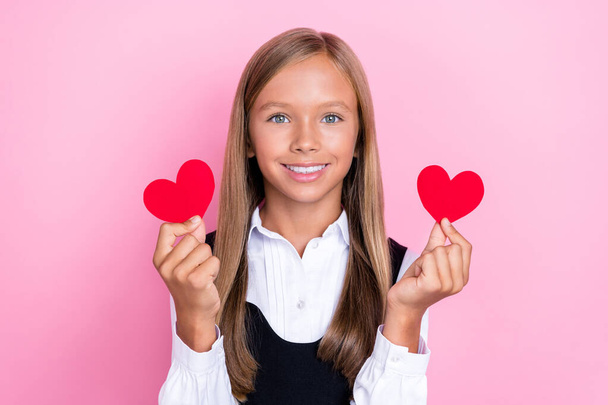 Φωτογραφία από γλυκό όμορφο χαρούμενο κορίτσι χέρι κατέχουν παρουσιάζοντας δύο μικρές κόκκινο χαρτί κάρτα Αγίου Βαλεντίνου απομονώνονται σε ροζ χρώμα φόντο. - Φωτογραφία, εικόνα