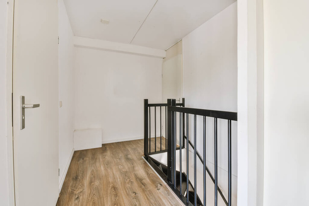 Suljettu valkoinen ovi huoneen lähellä kehystetty kuvia ja tyylikäs lamppu päälle portaikko kotona - Valokuva, kuva