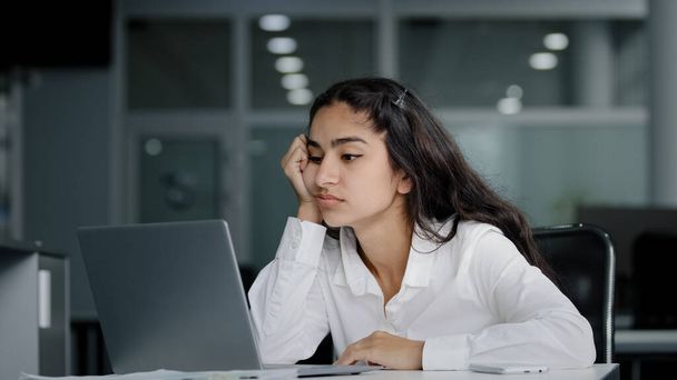 Dizüstü bilgisayarda yazan üzgün, tembel, genç bir kadın motivasyonsuz iş kadını bilgisayar başında çalışmaktan yorgun düşüyor. Sıkıcı, sıkıcı, sıkıcı bir işten dolayı dikkati dağılmış, yorgun düşüyor. - Fotoğraf, Görsel