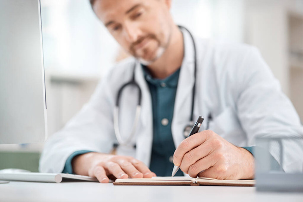 Taking notes to better his diagnosis. Closeup shot of a mature doctor writing notes in a medical office - 写真・画像