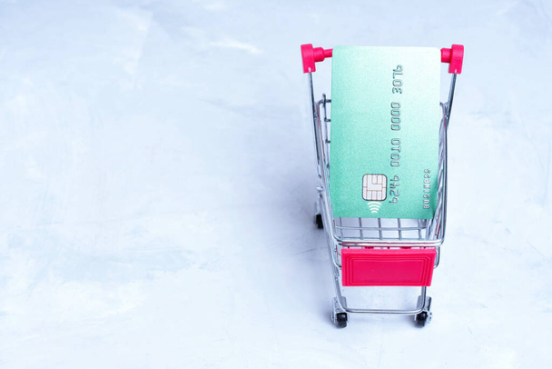 Credit card in a small push cart isolated on gray background, top view. - Φωτογραφία, εικόνα