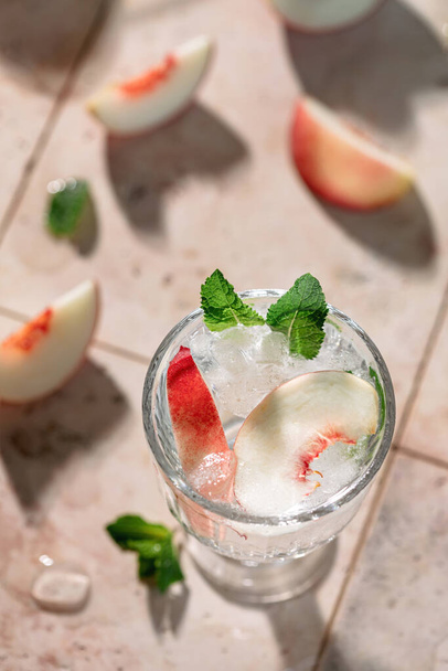 Preparation of a refreshing summer drink from peaches, ice and mineral water - Photo, Image