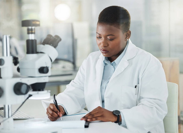 Aiming to produce precise data after thorough analysis. a young scientist writing notes while working in a lab - Zdjęcie, obraz