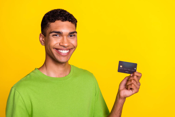 Closeup photo of young attractive handsome smiling positive guy hold debit bank card high percent recommend ad isolated on yellow color background. - Фото, зображення
