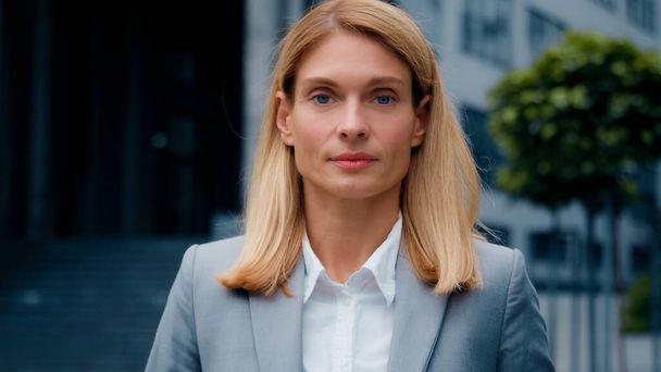 Female portrait young successful caucasian businesswoman blonde in formal suit looking at camera confident proud serious woman professional manager leader entrepreneur lawyer model posing outdoors - Photo, Image