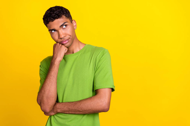 Photo of attractive young guy fist touch face look suspicious empty space dressed trendy green outfit isolated on yellow color background. - Foto, Imagem