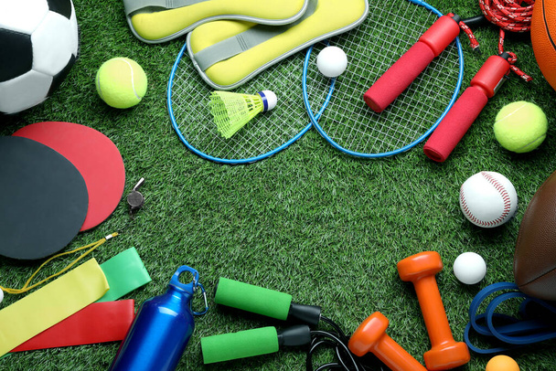 Set of different colorful sports equipment on green grass, flat lay. Space for text - Φωτογραφία, εικόνα