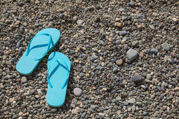 Stylish turquoise flip lops on pebble beach, above view. Space for text - Fotó, kép