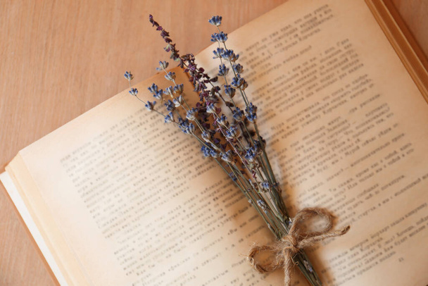 Open book with bunch of dried flowers on wooden table, closeup - Foto, afbeelding