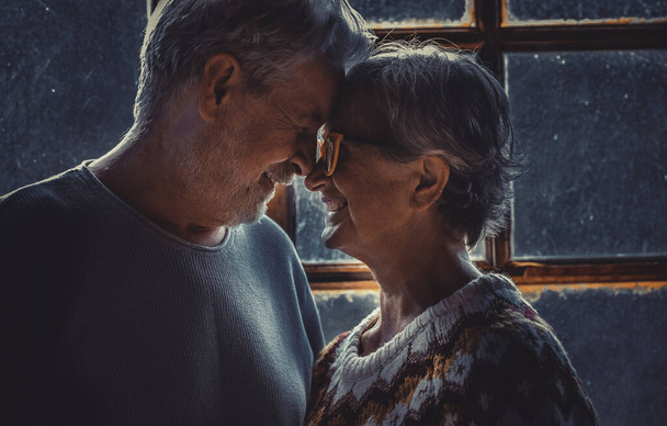 Idős idős pár a szerelemben és romantikus szabadidős tevékenység otthon szemtől szemben megható elülső és mosolygós kapcsolatban. Téli ünnep karácsony idő beltéri férfi és nő idős kor boldogság - Fotó, kép