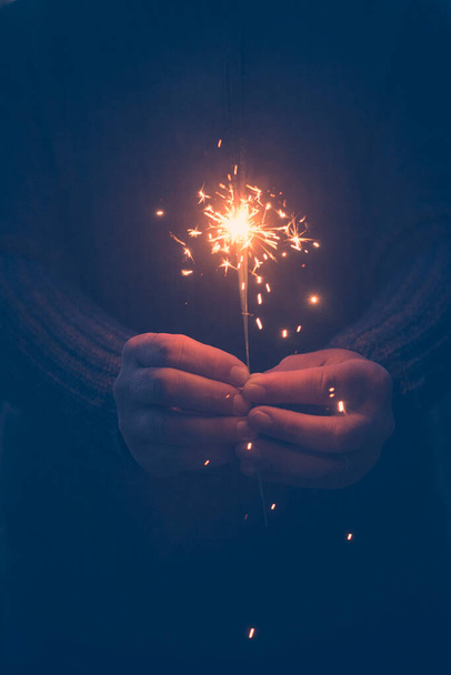  image of hands holding a fire sparkler to celebrate new year eve or christmas time. People close up for celebration and holiday fun. Freedom and hope. Daydreamer female - Photo, Image