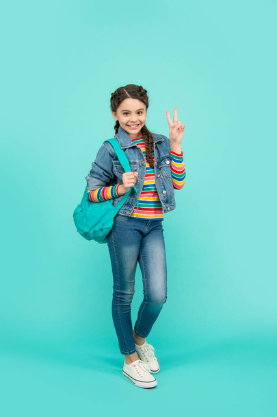 School education. Happy teen girl showing V sign blue background, school. Back to school. - Foto, afbeelding
