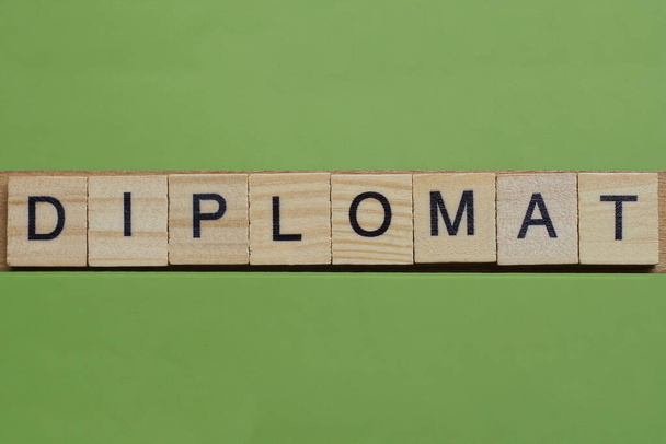 szó diplomata készült kis szürke fa betűk zöld könyv háttér - Fotó, kép