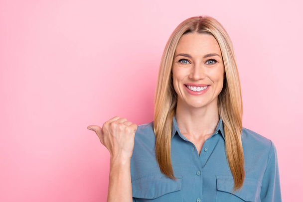 Closeup photo of young cheerful businesswoman wear blue blouse toothy smile finger pointing empty space recommend dentistry isolated on pink color background. - Foto, afbeelding