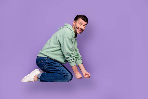 Full body photo of attractive young guy flying broomstick have fun wear trendy gray outfit isolated on violet color background. - Photo, image