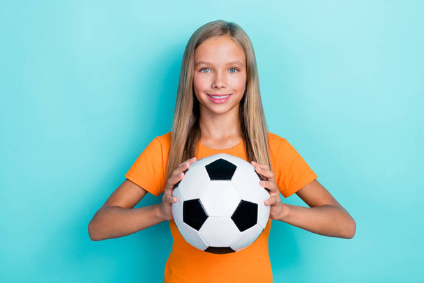 Photo of little cute positive blonde hair sportive girl hold soccer ball like hobby player school tournament isolated on aquamarine color background. - Foto, imagen