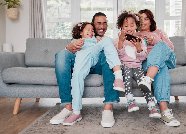 Den ganzen Tag bewirtet. eine glückliche Familie, die zu Hause gemeinsam ein Handy benutzt - Foto, Bild