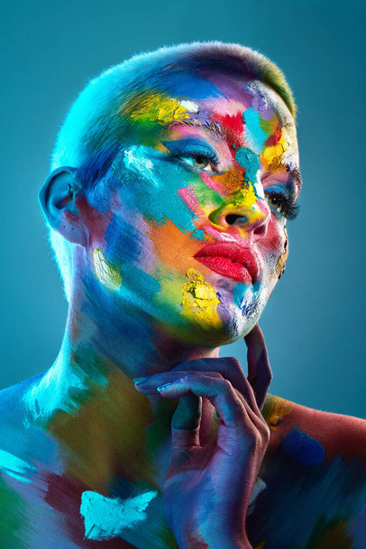 Take a closer look and youll discover all the multitudes. Studio shot of a young woman posing with multi-coloured paint on her face - Photo, image