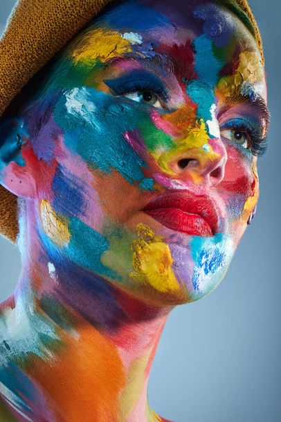 Sanatçıların düşündüğü şey genellikle renklerle ifade edilir. Yüzünde çok renkli boya ile poz veren genç bir kadının stüdyo fotoğrafı. - Fotoğraf, Görsel