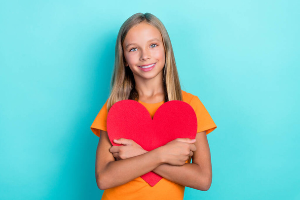 Photo of young little cute schoolkid girl blonde hair positive smile hug red paper heart good mood lovely feelings isolated cyan color background. - Foto, imagen