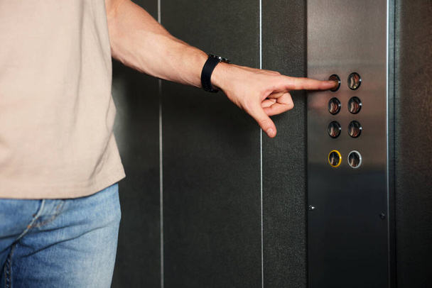 Hombre eligiendo piso en ascensor, vista de primer plano - Foto, imagen