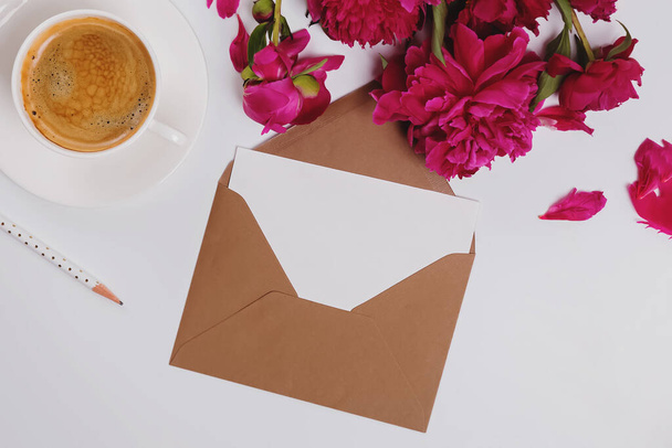 Greeting card in the envelope, flat lay with coffee and pink peonies, paper mock-up - Fotoğraf, Görsel