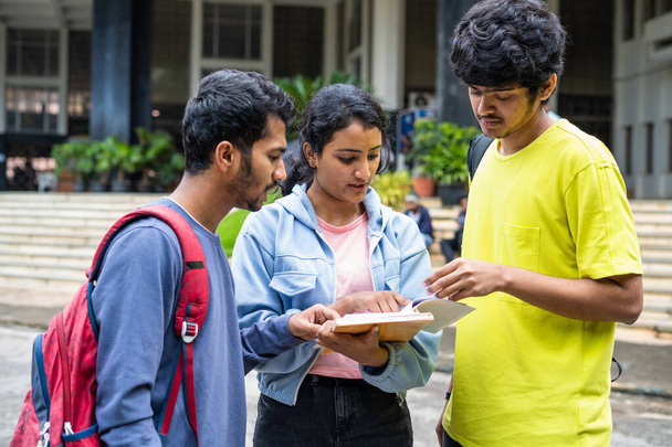 ομάδα των νέων ινδών φοιτητών απασχολημένος με τη συζήτηση του αναλυτικού προγράμματος κατά τη διάρκεια των εξετάσεων στο κολέγιο πανεπιστημιούπολη - έννοια της μάθησης συζήτηση και τη φιλία. - Φωτογραφία, εικόνα