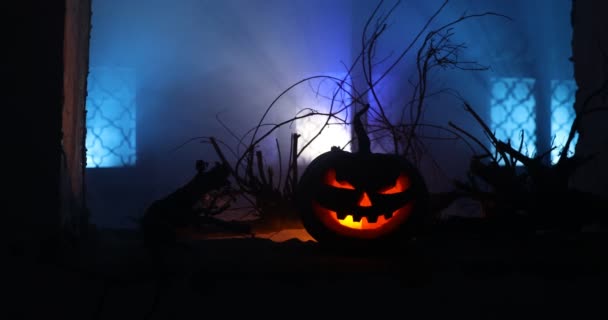 Enge Halloween pompoen in het mystieke huis venster 's nachts of Halloween pompoen in de nacht op verlaten kamer met raam. Selectieve focus  - Video