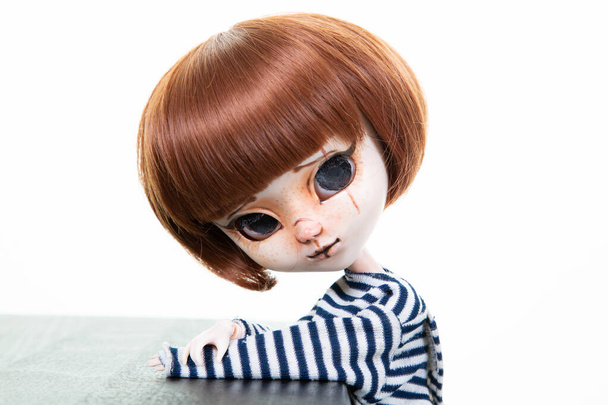 pěkný expresivní panenka s velkýma očima červené vlasy v modré košili v bílém pozadí - Fotografie, Obrázek