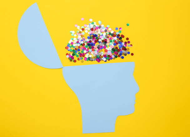 Apri la mente, festa, concetto di salute mentale, pensiero creativo. Silhouette di carta di testa umana con coriandoli su sfondo giallo - Foto, immagini