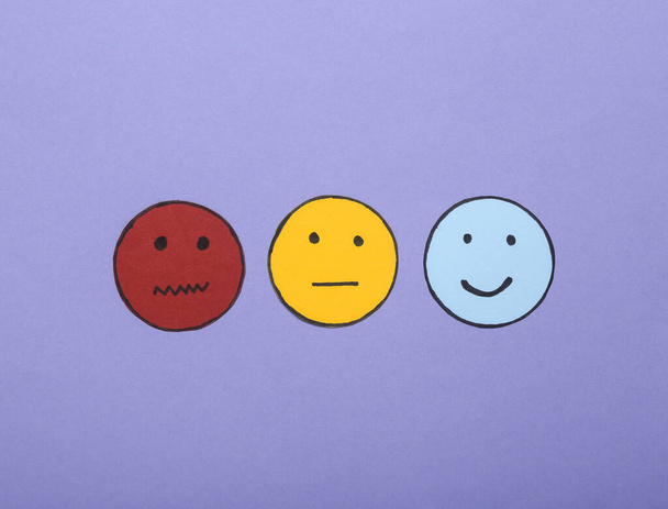 Umfrage zur Kundenzufriedenheit. Glückliches, neutrales und trauriges Gesicht auf violettem Hintergrund. Ansicht von oben - Foto, Bild